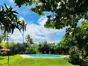 a swimming pool in a park with trees at Crown Holiday Village near Marawila in Nattandiya +45 photos
