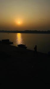 une personne se promenant sur la rive d'un lac au coucher du soleil dans l'établissement Tandon Lodge, à Varanasi