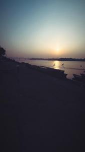 zachód słońca nad wodą z łodziami w obiekcie Tandon Lodge w mieście Waranasi