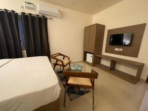 a bedroom with a bed and a table and a tv at Baga Keys by RJ14 in Old Goa