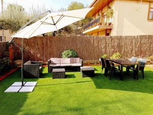 eine Terrasse mit einem Tisch und einem Regenschirm auf Gras in der Unterkunft Secrets of Montserrat in El Bruc