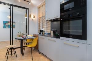 una cocina con armarios blancos y una mesa con sillas amarillas en Apartament Nad Motławą Seredyńskiego by Renters en Gdansk
