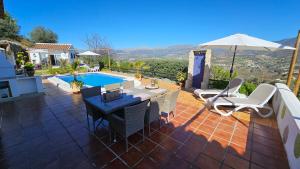 een patio met een tafel en stoelen en een zwembad bij Casita Johanna in Viñuela