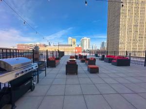 un patio en la azotea con mesas, sillas y una parrilla en McCormick Place with city view 2br/2ba - optional Parking & Gym, en Chicago