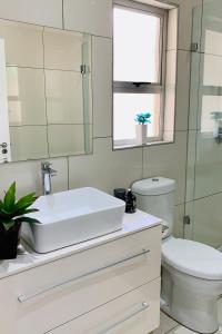 een witte badkamer met een wastafel en een toilet bij Essence Lifestyle Self-Catering Accommodation - 1523 Hochland Park in Windhoek