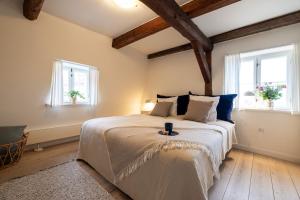 a bedroom with a large bed with two windows at Købmandsgaarden Kerteminde in Kerteminde