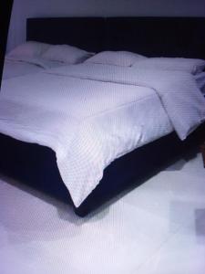 a bed with a white comforter on top of it at St Theresas apartment Lodge 3 in Lekki