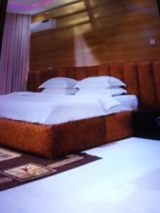 1 cama con sábanas blancas y almohadas en una habitación en St Theresas apartment Lodge 3, en Lekki