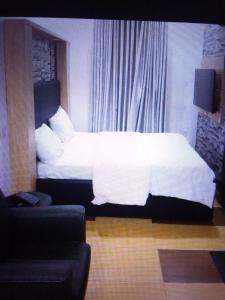 1 dormitorio con cama con sábanas blancas y sofá en St Theresas apartment Lodge 3 en Lekki
