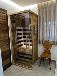 um chuveiro com uma porta de vidro e uma cadeira de madeira em Hotel Kotnik Superior - Small & Beautiful em Kranjska Gora