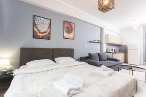 a white bedroom with a large bed and a couch at Downtown Seaside Studios in Thessaloniki