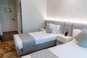 ein Hotelzimmer mit 2 Betten mit weißer Bettwäsche in der Unterkunft eStay Hotel in Dubai