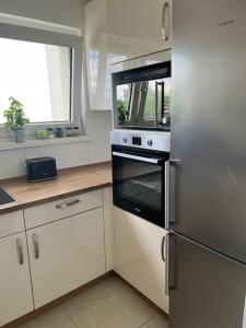 a kitchen with a stainless steel refrigerator and white cabinets at Schöne Wohnung Nähe Düsseldorf Messe und Flughafen in Duisburg