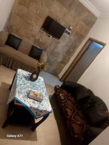 a living room with a table and a couch at اوليفيا للشقق الفندقية in Amman