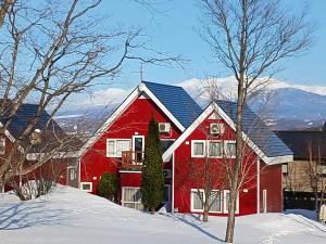 a red house with snow in front of it at Cottage Morino Nakamatachi in Furano