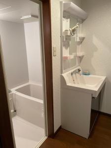 a white bathroom with a sink and a bath tub at MONJUNO FUKUCHI in Kamikishida