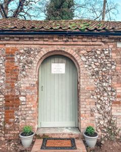 a brick building with a green door with two pots at The Hideaway in Fakenham