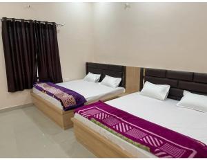 two beds sitting in a room withskirts at Uma Hotel, Chitrakoot in Sītāpur Mūāfi