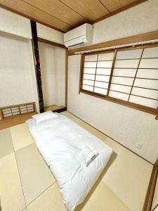 a large white bed in a room with a window at 最大10名で泊まれる貸別荘日本橋駅徒歩5分黒門市場に隣接し道頓堀 难波 心斎橋徒歩圏内 in Osaka
