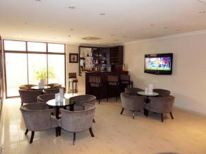 um restaurante com mesas e cadeiras e uma televisão de ecrã plano em S & S Hotel & Suites em Lagos