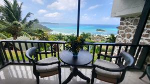 a balcony with chairs and a table with a view of the ocean at Mango Lodge in Anse Volbert Village