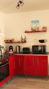 a kitchen with red cabinets and a black counter top at Appartement cosy au centre ville de Menton in Menton