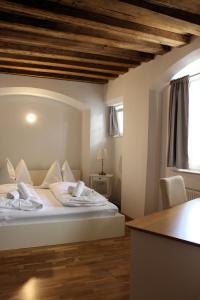 Schlafzimmer mit einem Bett mit weißer Bettwäsche und einem Tisch in der Unterkunft City Center Golden Roof in Innsbruck