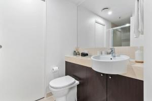 a white bathroom with a sink and a toilet at Lux Retreat - Sauna pool & prime location in Cairns +11 photos