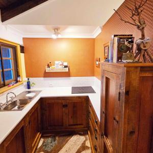 una cocina con armarios de madera y fregadero en The Gamekeepers Cottage en Mount Tamborine