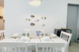 biały stół jadalny z białymi talerzami i krzesłami w obiekcie Santorini Holiday Resort Style Staycation 3 rooms w mieście Shah Alam