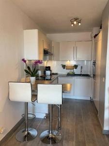 a kitchen with white cabinets and a table with chairs at Magnifique 2 pièces Juan Les Pins in Antibes