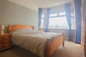 a bedroom with a bed with blue curtains and a window at Avocet View *sleeps 10* in Exmouth