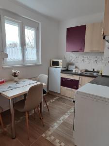 eine Küche mit einem Tisch und Stühlen sowie eine Küche mit lila Schränken in der Unterkunft Hegin Exclusiv Home in Budapest