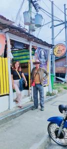 a man and a woman standing in front of a building at Puerto Galera Transient Kubo Guest Place in Puerto Galera