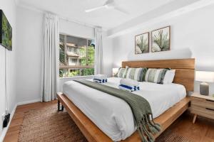 ein Schlafzimmer mit einem großen Bett mit einem hölzernen Kopfteil in der Unterkunft The Nest Cairns - 4 pools BBQ & Resort in Cairns North + 29 Fotos