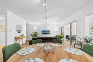 ein Wohnzimmer mit einem Tisch und grünen Stühlen in der Unterkunft The Nest Cairns - 4 pools BBQ & Resort in Cairns North