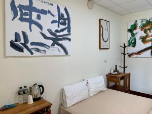 1 dormitorio con 1 cama y pinturas en la pared en People Hostel Taiwan Image Calligraphy Museum, en Baihe