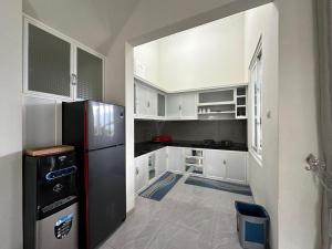 Una cocina con gabinetes blancos y un refrigerador negro. en Daisha Villa - Batu (Private Pool), en Punten