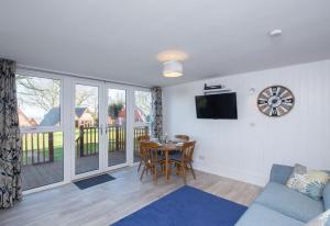 een woonkamer met een tafel en een klok aan de muur bij Chalet Sixtysix in Deal