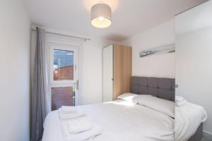 um quarto com uma cama com lençóis brancos e uma janela em Chalet Sixtysix em Deal