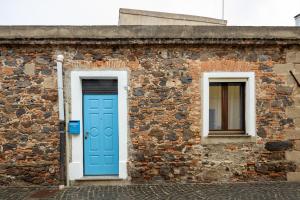 a brick building with a blue door and two windows at Casa Miriam in Oristano