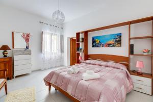 a bedroom with a large bed with a pink bedspread at Casa Miriam in Oristano