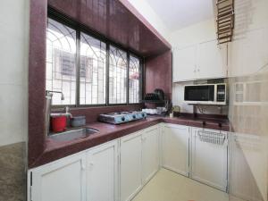 d'une cuisine avec des placards blancs, un évier et une fenêtre. dans l'établissement Solace - 1 BHK - Walk away from Carter road, à Mumbai