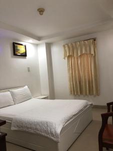 a bedroom with a white bed and a window at Seven Stars Hotel in Ho Chi Minh City +1 photo