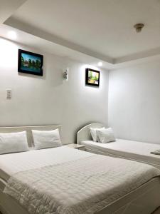 two beds in a hotel room with two monitors on the wall at Seven Stars Hotel in Ho Chi Minh City