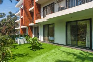 a green lawn in front of a building at Etereo Stays, Luxury Premium Apartments, Arpora, Goa in Arpora