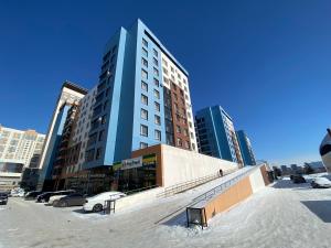 a tall building with cars parked in a parking lot at Astana Arena Apartment in Astana