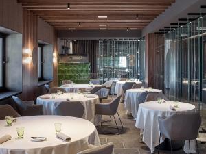 uma sala de jantar com mesas e cadeiras brancas em Hotel San Giacomo Spa&Gourmet em Brentonico