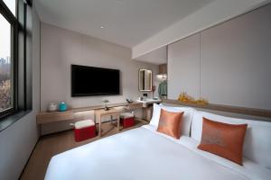 a bedroom with a large white bed and a flat screen tv at SSAW Garden Hotel Beijing in Beijing