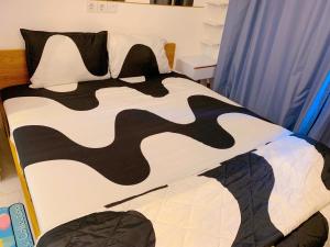a bed with a black and white comforter and pillows at Apartemen Sky House BSD by Benchmark in Tangerang